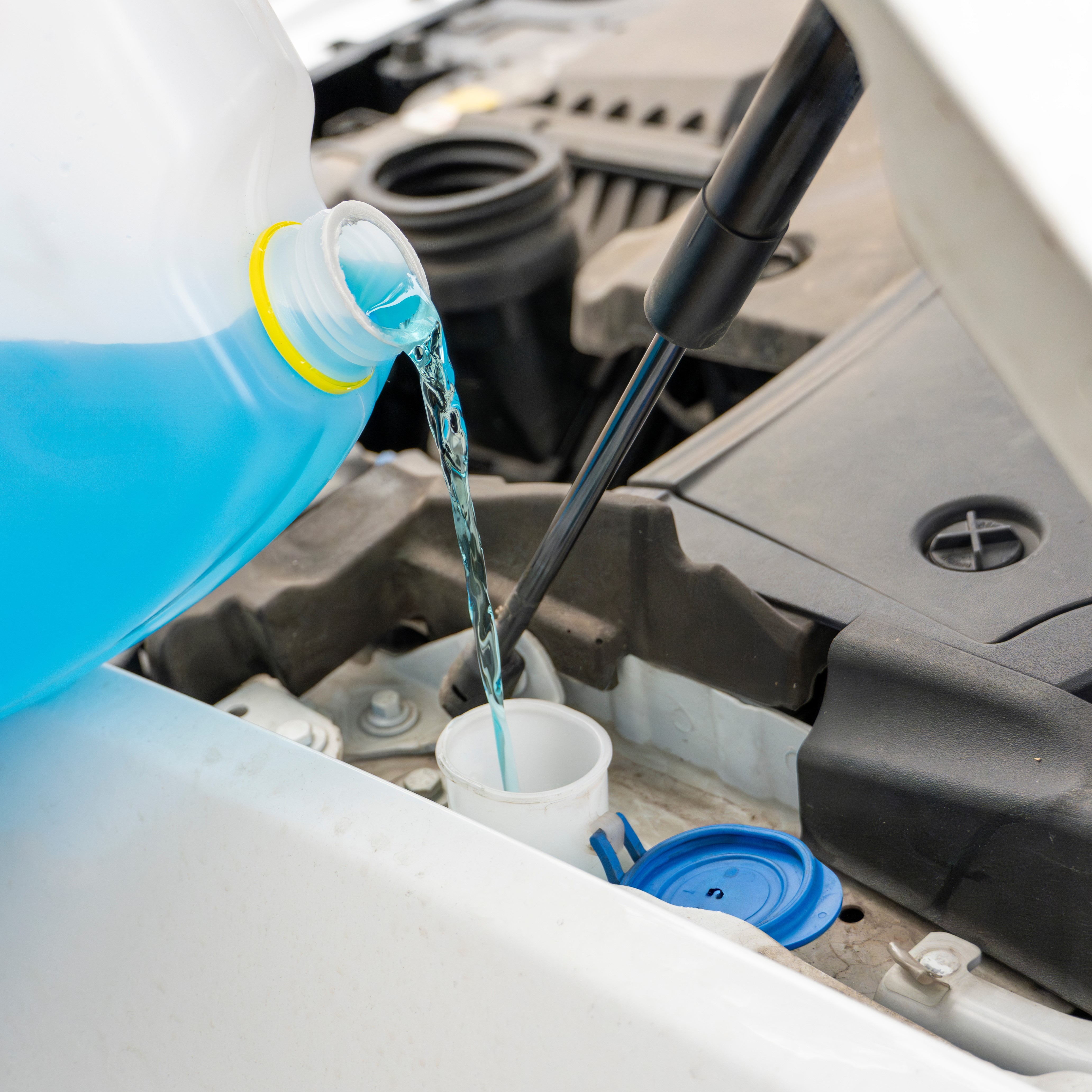 Pouring antifreeze. Filling a windshield washer tank with an antifreeze in winter cold weather.