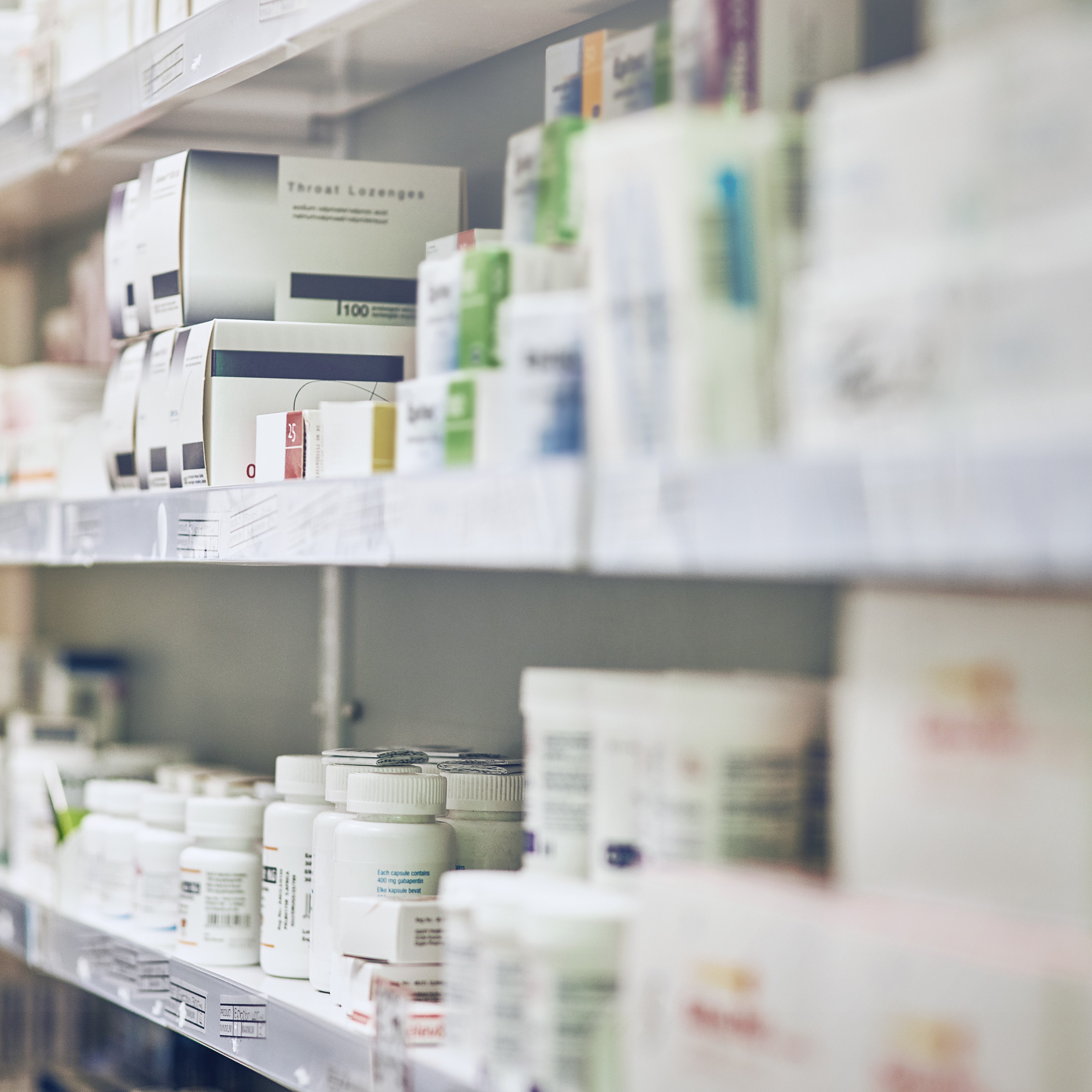 Closeup, pharmacy and medicine with healthcare, pills and shelf with boxes, bottles and treatment. Zoom, medication and package with container, retail and store with pharmaceutical, items or products