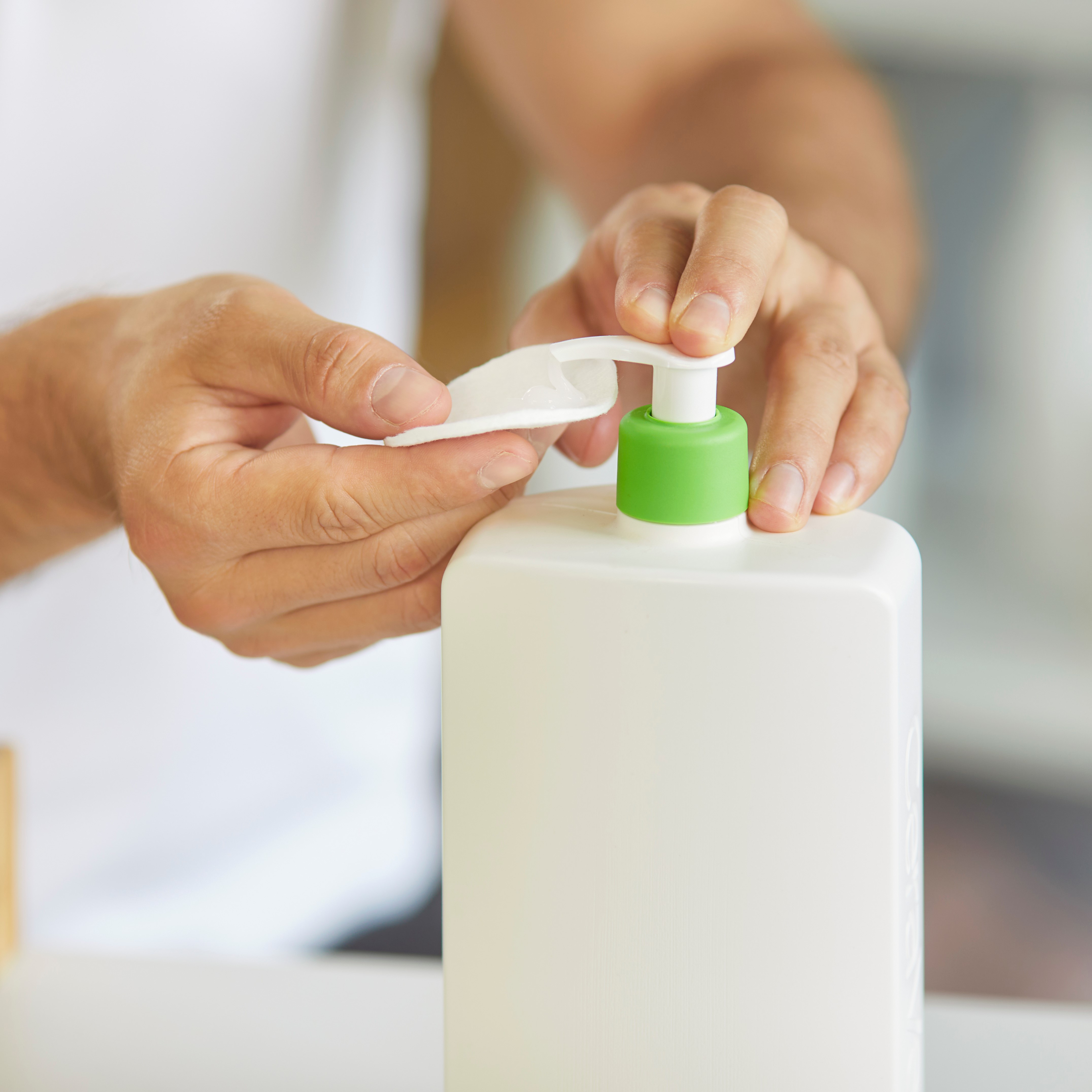Close-up of male hands holds cotton pad and dispensing liquid cosmetic product