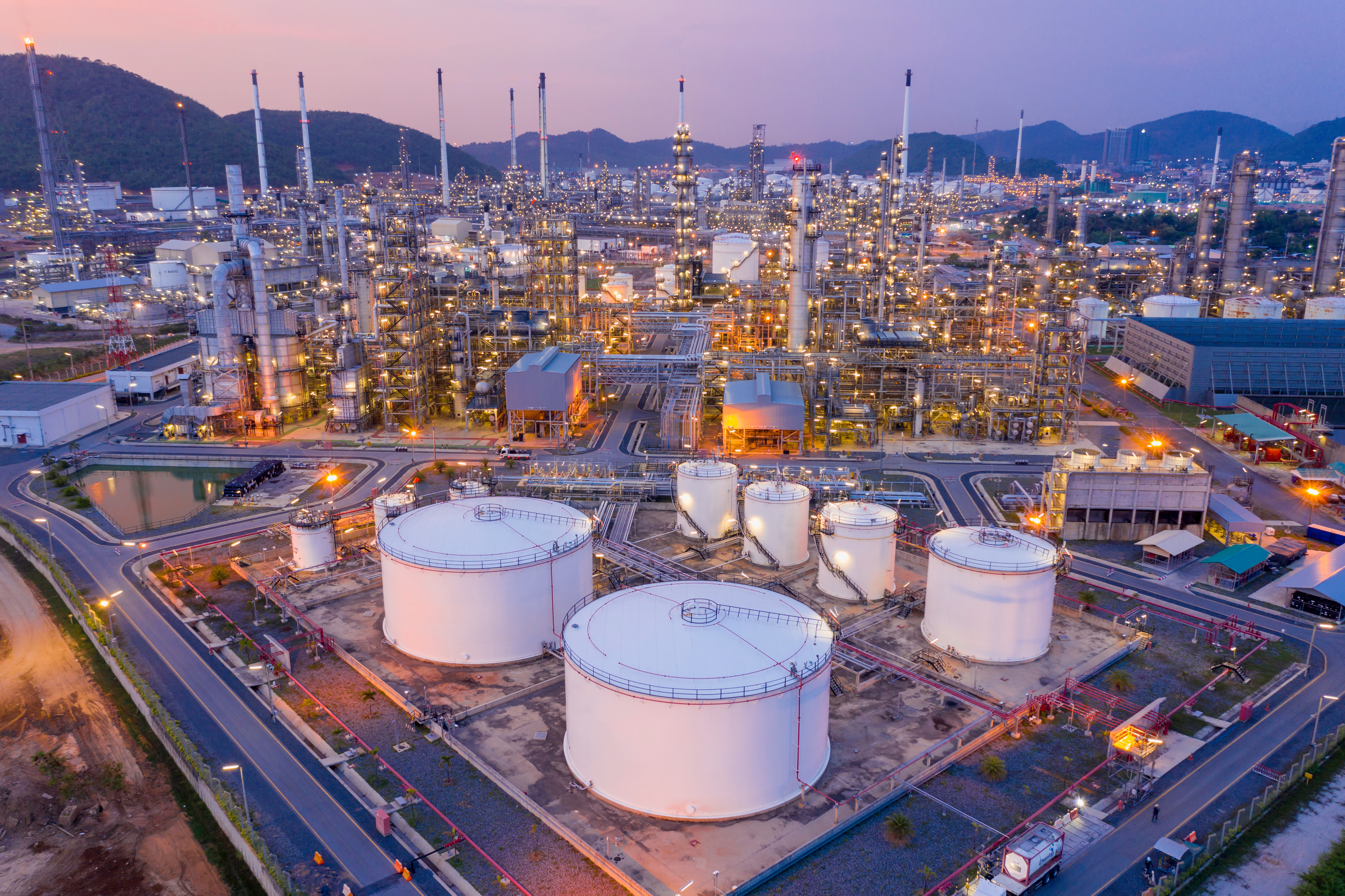 Aerial view Refinery and oil storage tanks at dusk and night. Petrochemical and energy oil industries.