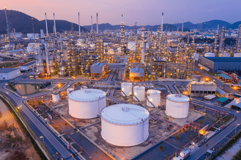 Aerial view Refinery and oil storage tanks at dusk and night. Petrochemical and energy oil industries.
