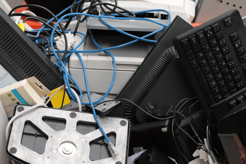 a pile of plastic technology waste and used broken office equipment heaped in a rubbish bin being taken for disposal
