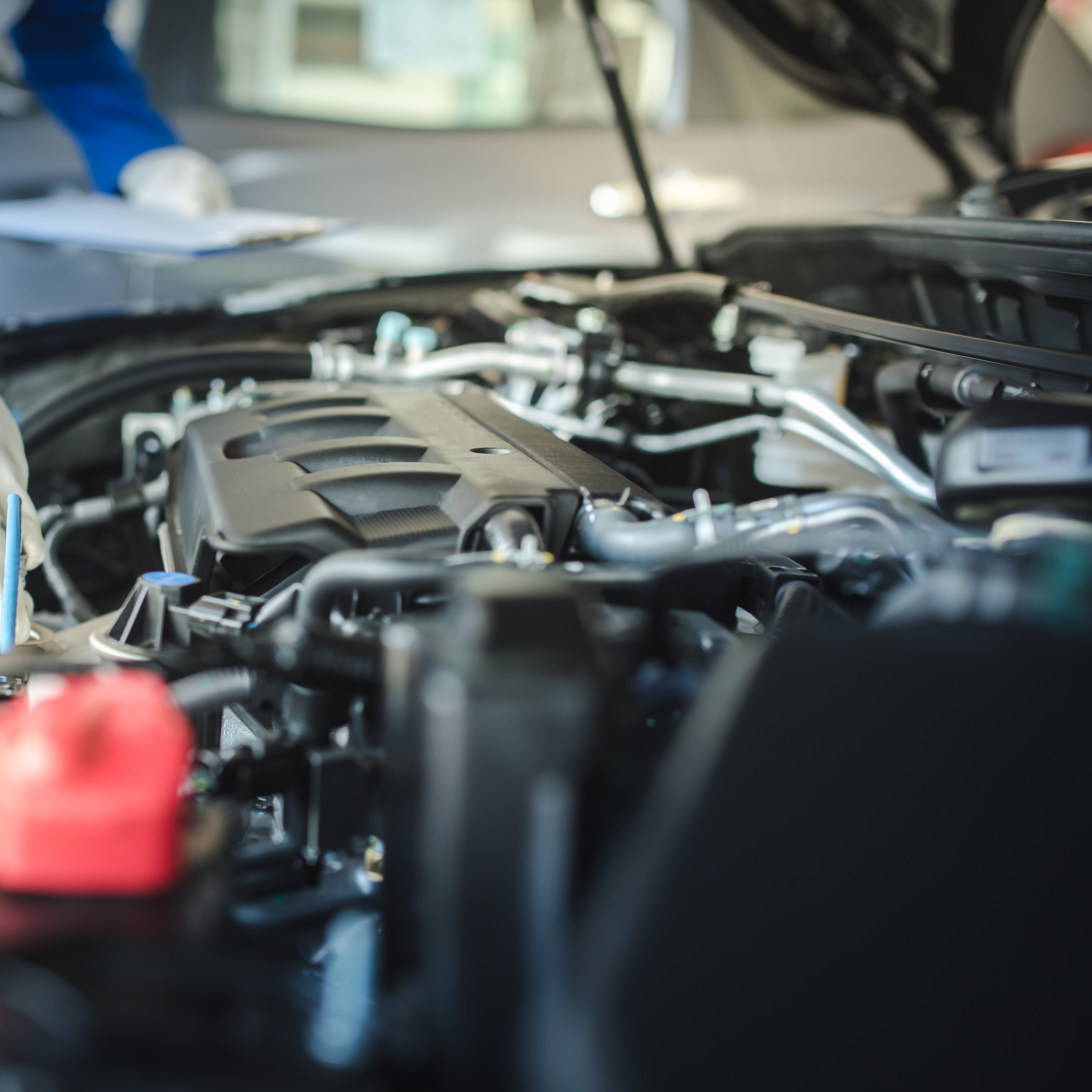Cropped image of handsome mechanic in uniform is working in auto service. Car repair and maintenance.