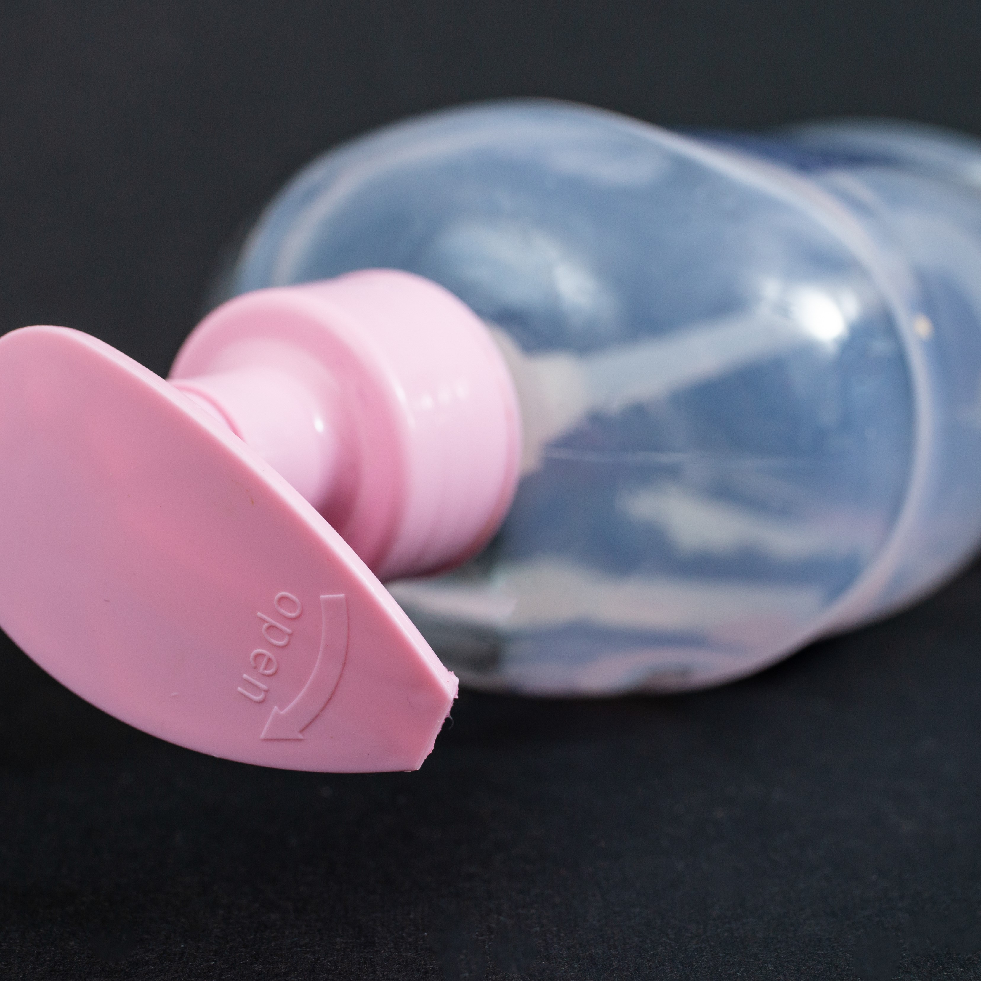 Empty plastic liquid soap bottle with pink pump cap, on black background