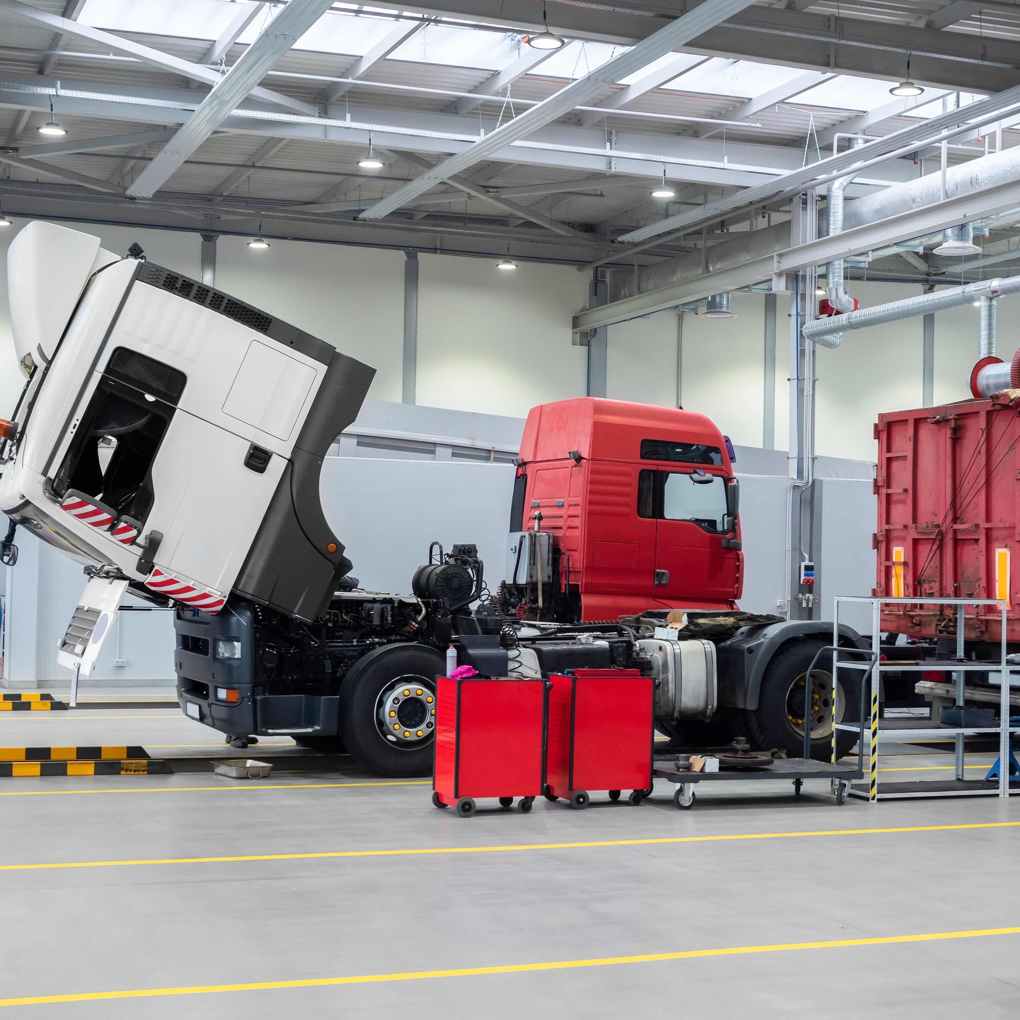 Servicing and repairing trucks in a large garage. Car service and truck maintenance. Auto mechanic checking the truck in the garage.